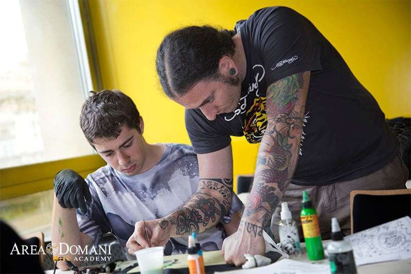Tutor AreaDomani che segue uno studente al lavoro su un tatuaggio